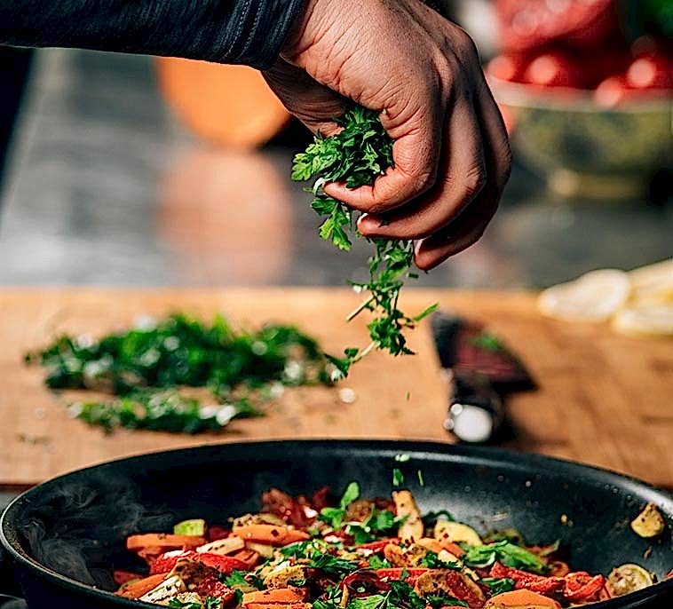 hand adding parsley into frying pan with vegetable 2021 08 27 09 01 22 utc2